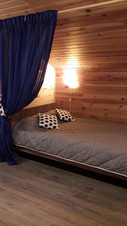 a bed in a log cabin with a blue curtain at Good Luck Holiday Homes in Smolenka