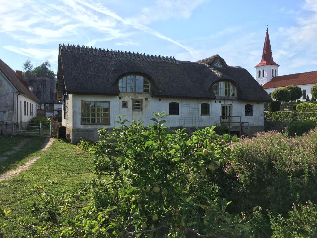 una casa blanca con techo negro y una iglesia en Ga Prästgården i Rörum en Simrishamn