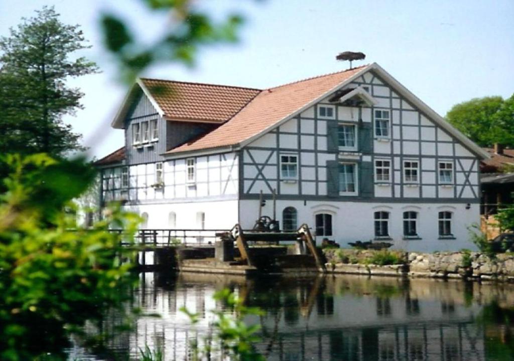 un gran edificio blanco sentado junto a un cuerpo de agua en Wipperaublick in der Oldenstädter Wassermühle, en Uelzen