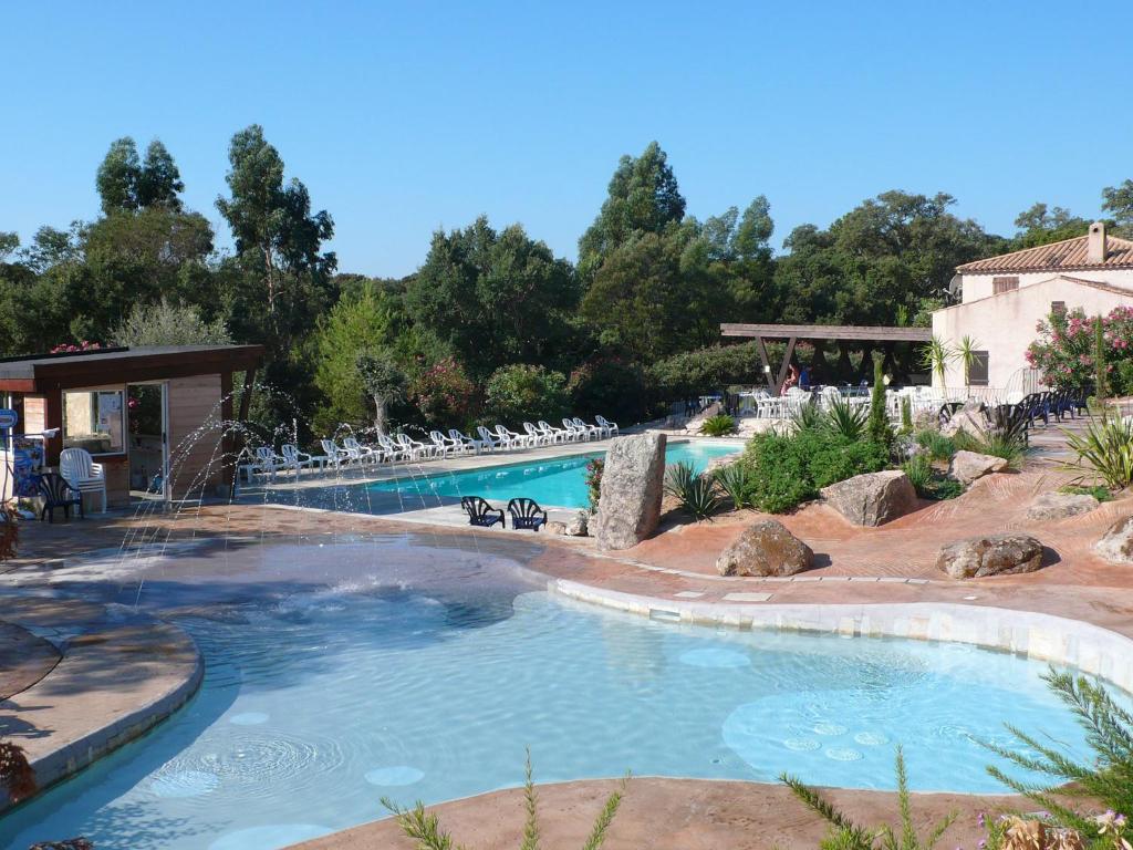 a swimming pool in a resort with chairs in it at Camping La Vetta in Porto-Vecchio