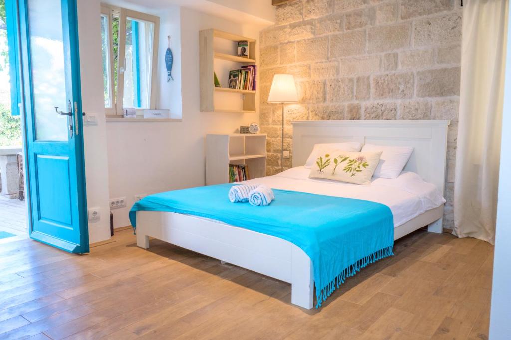 a bedroom with a white bed with a blue blanket at ECO Aparthotel The Dreamers's Club in Lumbarda
