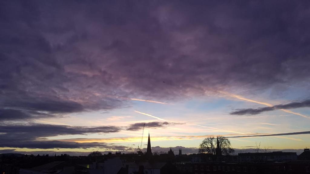 a cloudy sky with a church steeple in a city at Central Penthouse with Hot Tub & Views 23 in Cheltenham