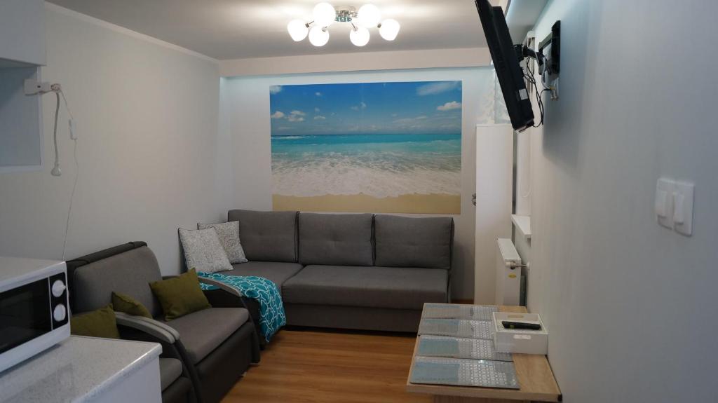 a living room with a couch and a view of the ocean at Apartament Bajka in Rumia