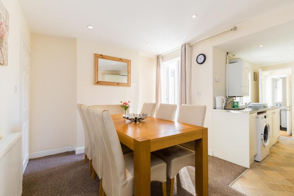 a dining room with a wooden table and white chairs at Leamington Spa Town House 2-Bed, 2 Bath in Leamington Spa