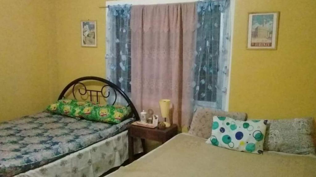 a bedroom with a bed and a window and a chair at John's M Den Tagaytay City in Tagaytay
