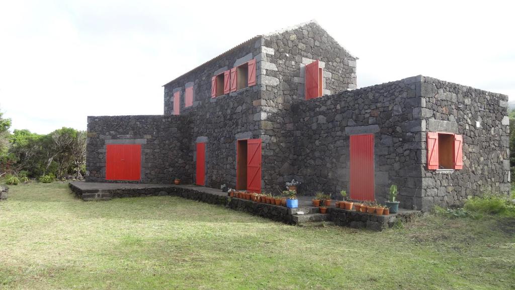 ein schwarzes Steinhaus mit roten Türen und Fenstern in der Unterkunft Retiro dos Bons Sinais in São Roque do Pico