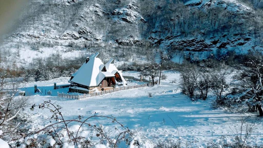 a small house covered in snow in front of a mountain at Vila Piramida in Bitola