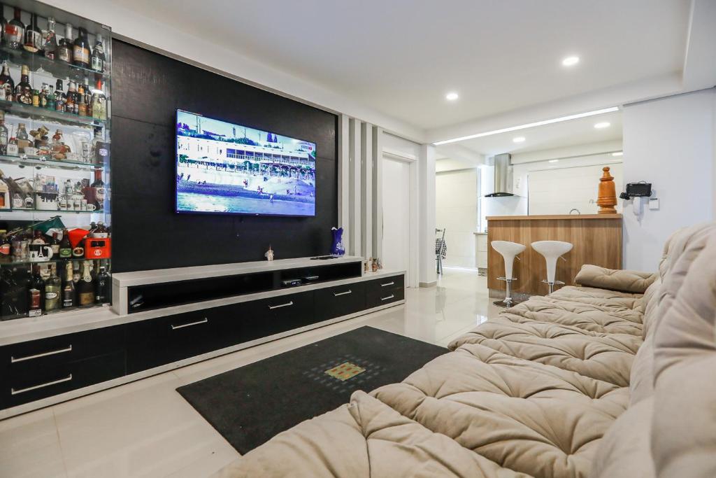 a living room with a bunch of chairs and a flat screen tv at Foz Cobertura 3 suítes in Foz do Iguaçu