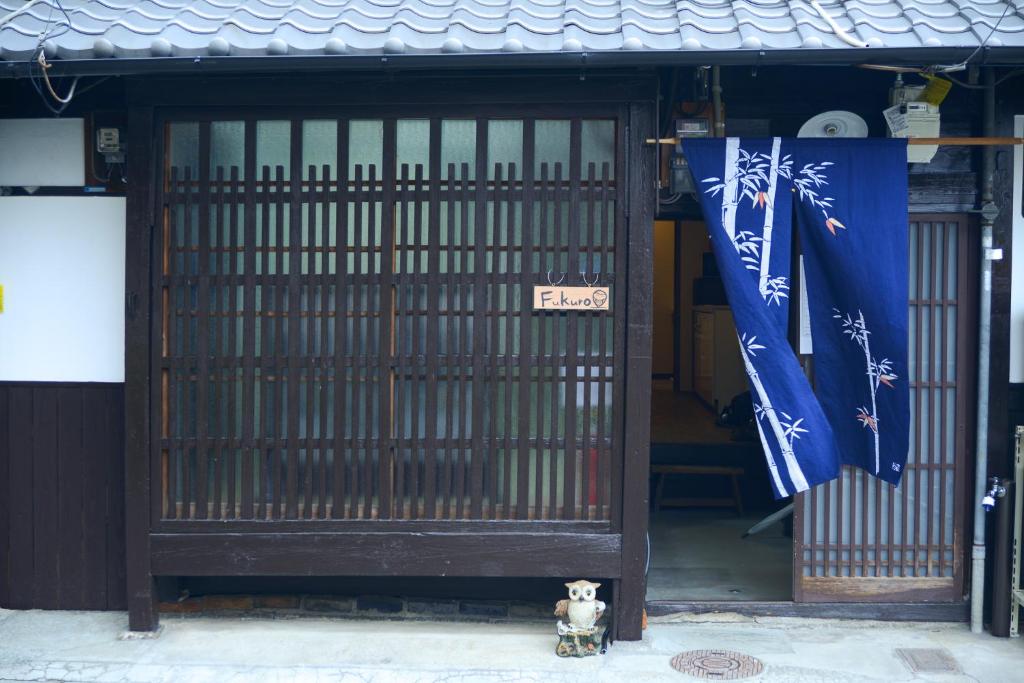 a dog sitting in front of a door with flags at Nishioji FUKURO 西大路梟 in Kyoto
