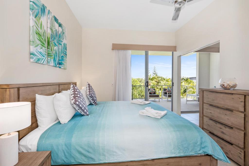 a bedroom with a large blue bed and a balcony at Drift Apartments - Tweed Coast Holidays ® in Kingscliff