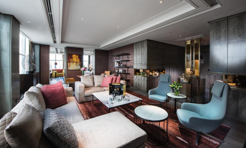 A large lounge with sofas, blue armchairs, coffee tables and a built-in bar or display area.