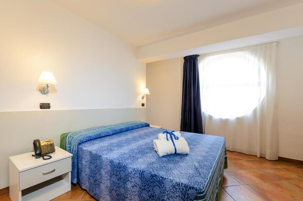 a hotel room with a bed with a blue blanket at Le Tartarughe Aparthotel in Letojanni