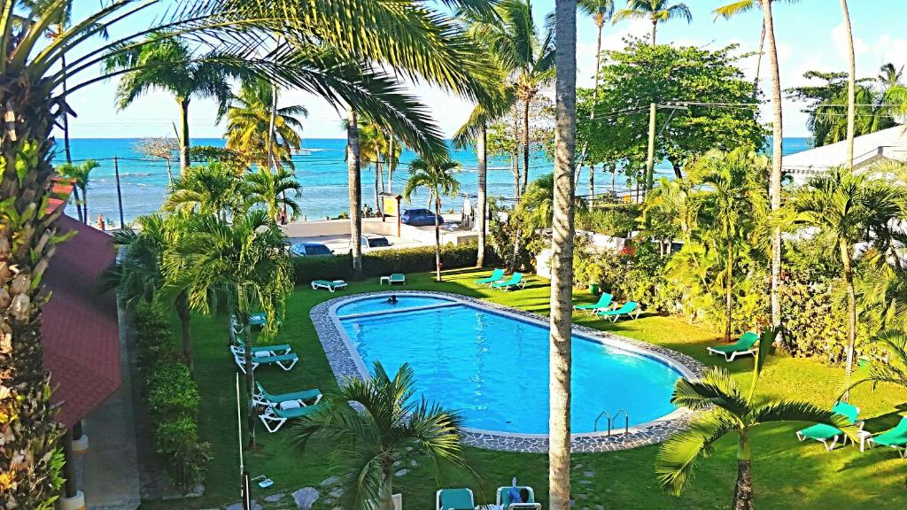 an overhead view of a swimming pool with palm trees and the ocean at La Dolce Vita Beachfront Hotels, Las Terrenas, Samana in Las Terrenas
