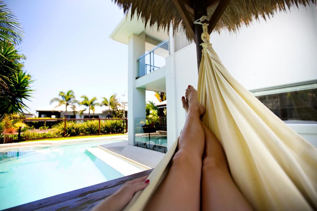 a woman laying in a hammock next to a swimming pool at THE BOARDWALK Relaxing Beachside Family Entertainer in Marcoola