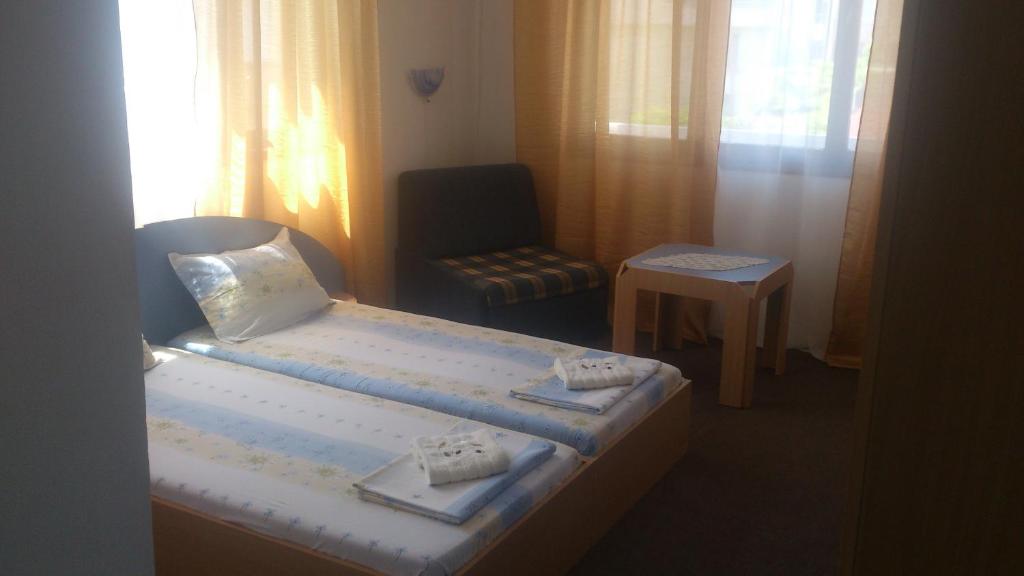 una habitación de hotel con 2 camas y una silla en Svetla Guest House en Primorsko