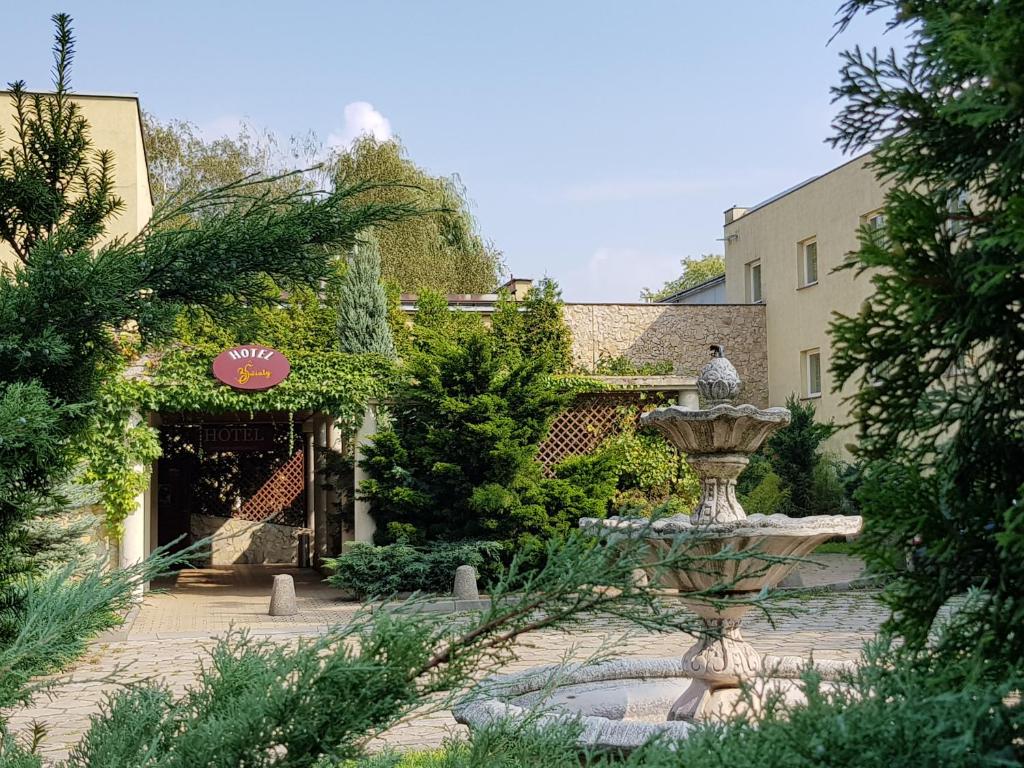 un jardín con una fuente frente a un edificio en Hotel Trzy Światy Spa & Wellness Rajska WySpa, en Gliwice