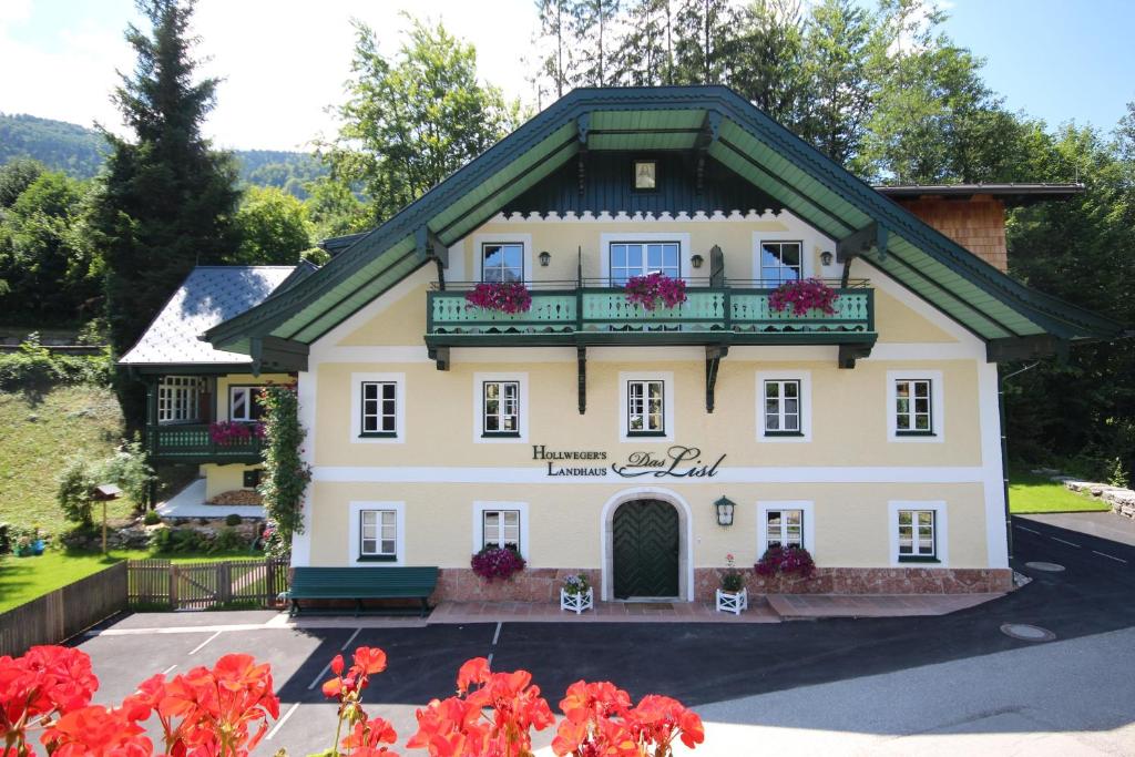 una gran casa blanca con flores en el balcón en Hollwegers Landhaus - Das Lisl en Sankt Gilgen