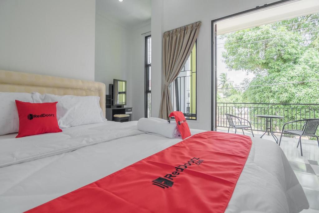 a bedroom with a large bed and a balcony at RedDoorz near Sultan Thaha Airport Jambi in Jambi