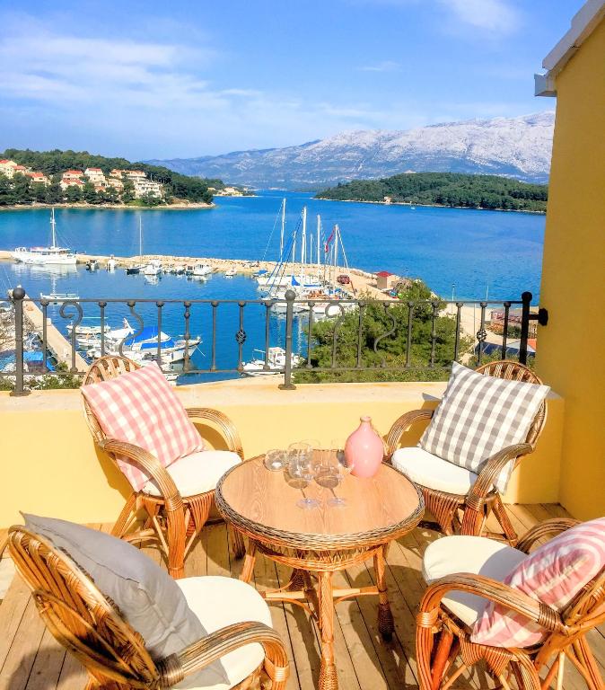 a balcony with chairs and a table and a view of a harbor at ECO Aparthotel The Dreamers's Club in Lumbarda
