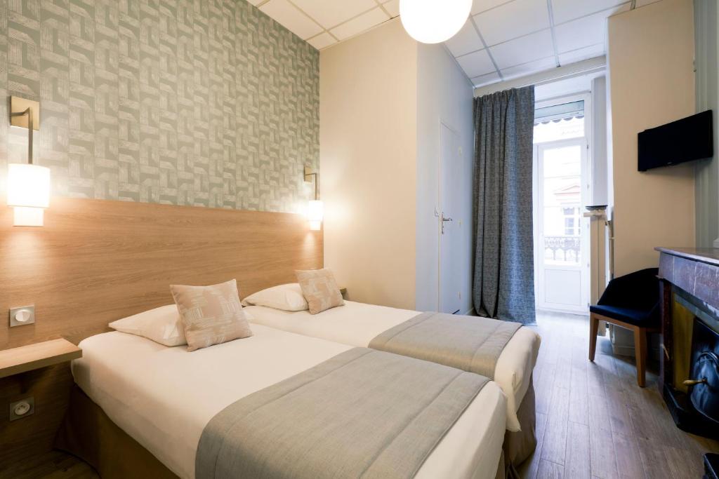 a hotel room with two beds and a television at Hôtel du Dauphin in Lyon