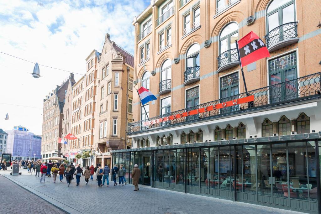 een groep mensen die door een straat voor gebouwen lopen bij Hotel Amsterdam De Roode Leeuw in Amsterdam