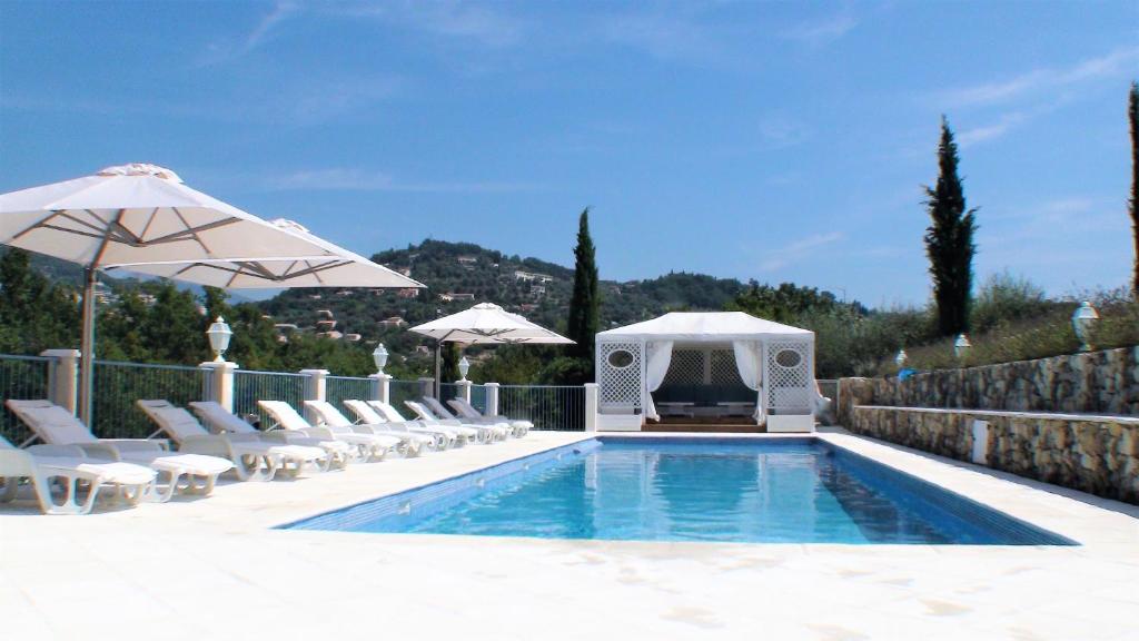 a swimming pool with white chairs and umbrellas at B&B with charm, quiet, kitchen, sw pool. in Grasse