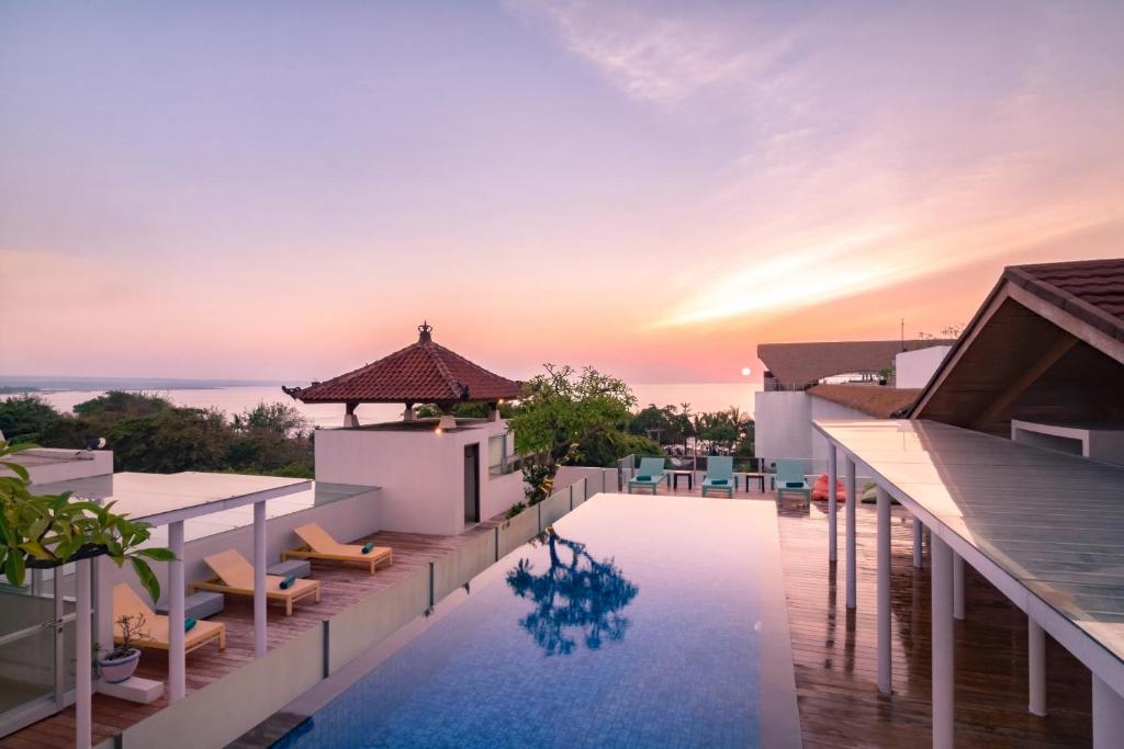 vistas a la piscina infinita de un complejo con puesta de sol en Kuta Beach Hotel, en Kuta