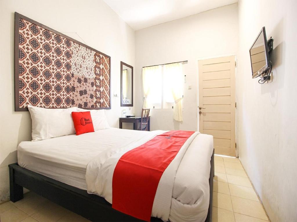1 dormitorio con 1 cama grande con almohadas rojas en Reddoorz Syariah near Wijilan Yogyakarta, en Yogyakarta