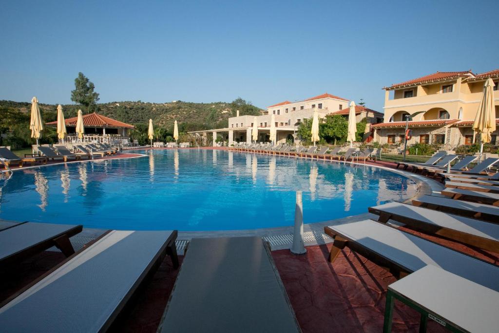 a large swimming pool with lounge chairs and umbrellas at Aktaion Resort in Gythio