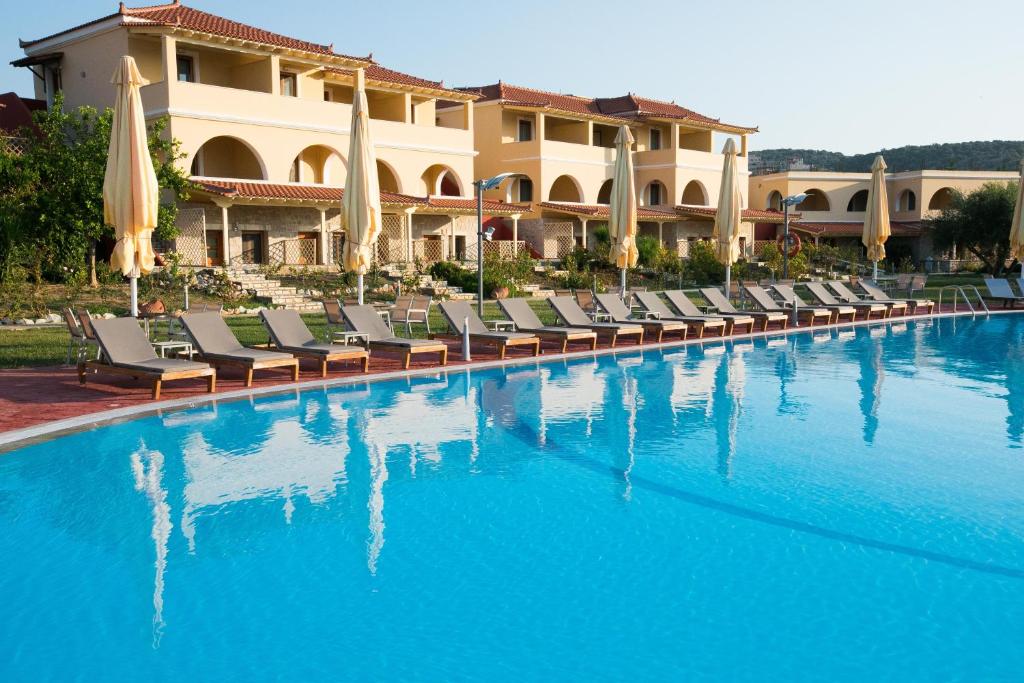 a large swimming pool with chairs and a hotel at Aktaion Resort in Gythio