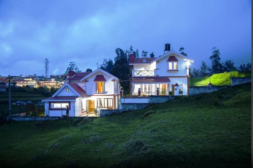 a white house on top of a hill at Pine View Stay Ooty in Ooty