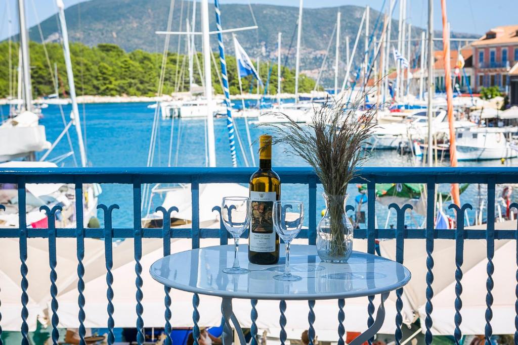 Una botella de vino y dos copas en una mesa en un balcón. en Authentic Suites in Fiscardo (Archontiko), en Fiskardho