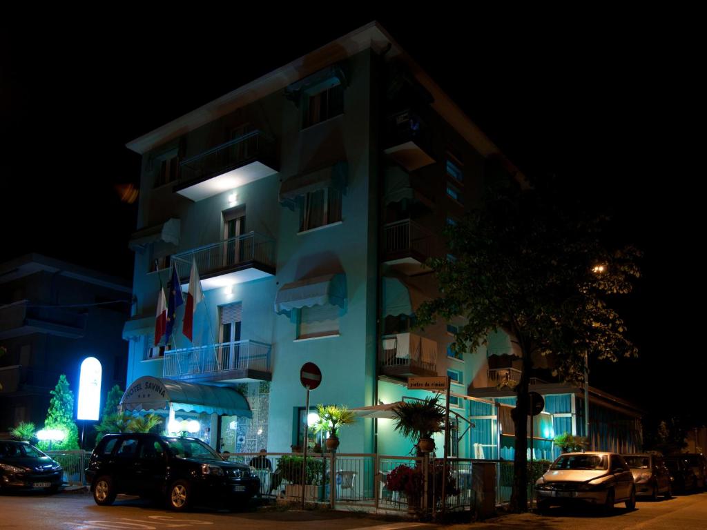a building with cars parked in front of it at night at Hotel Savina in Rimini