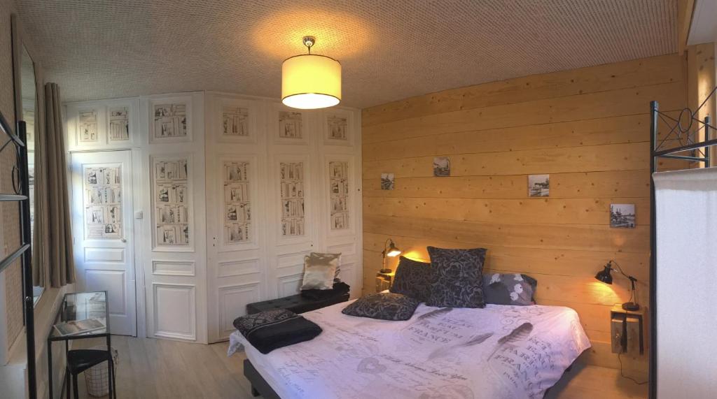 1 dormitorio con 1 cama en una habitación con paredes de madera en La Maison Du Bulot, en Fruges