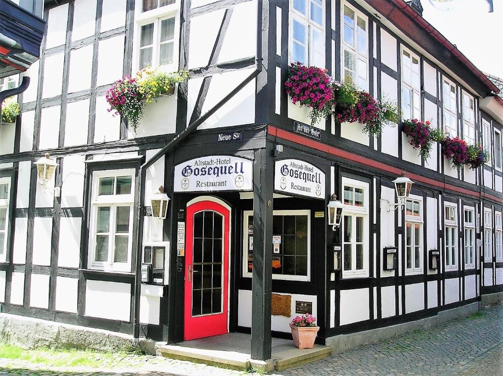 ein schwarzweißes Gebäude mit einer roten Tür in der Unterkunft Altstadt-Hotel Gosequell in Goslar