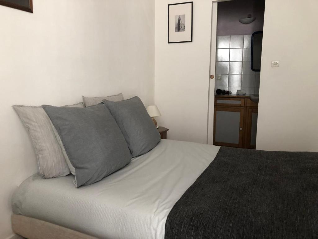 uma cama branca com almofadas cinzentas num quarto em Levis Charming Place em Paris