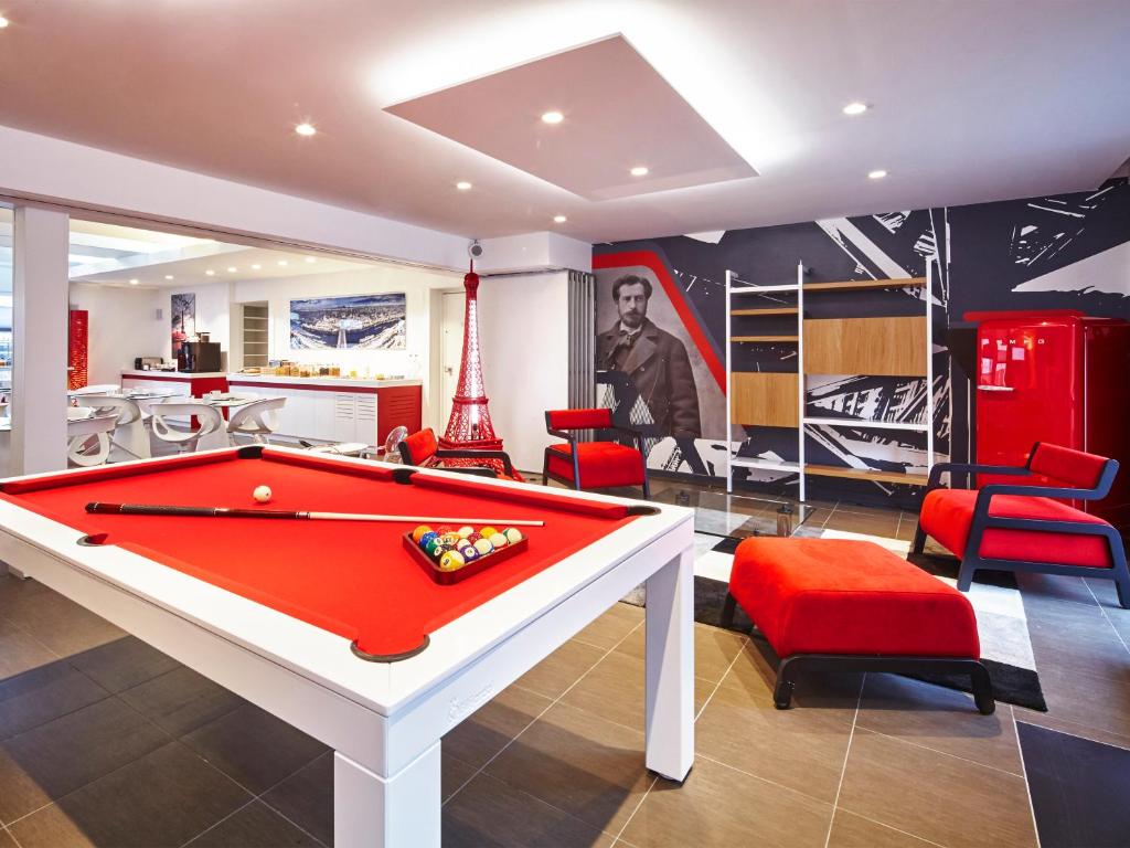 a living room with a pool table and red chairs at Kyriad Colmar Centre Unterlinden in Colmar