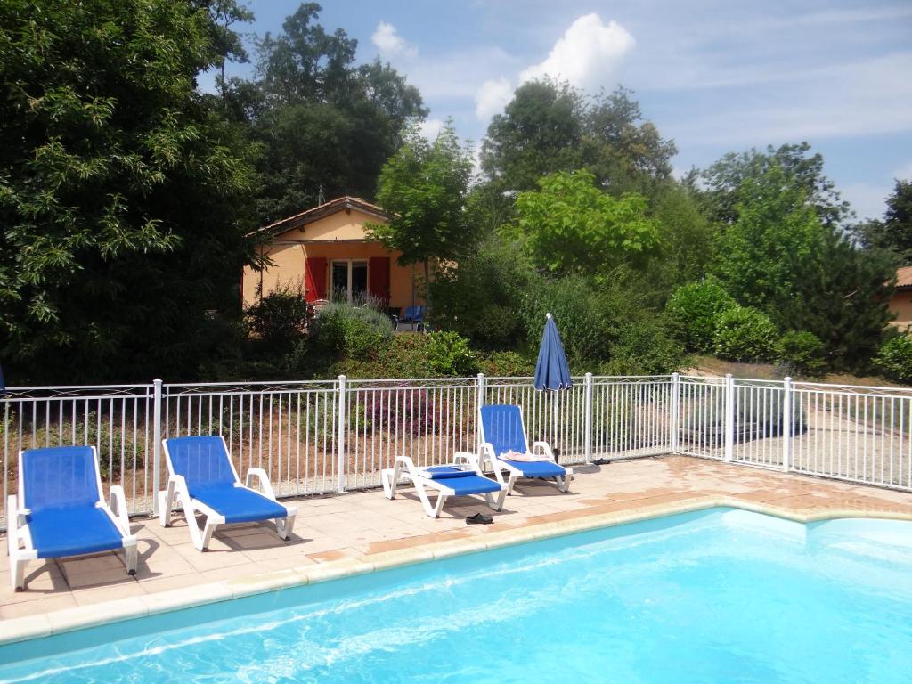 een zwembad met 3 ligstoelen en een hek bij Les Hauts du Coustalier in Doissat
