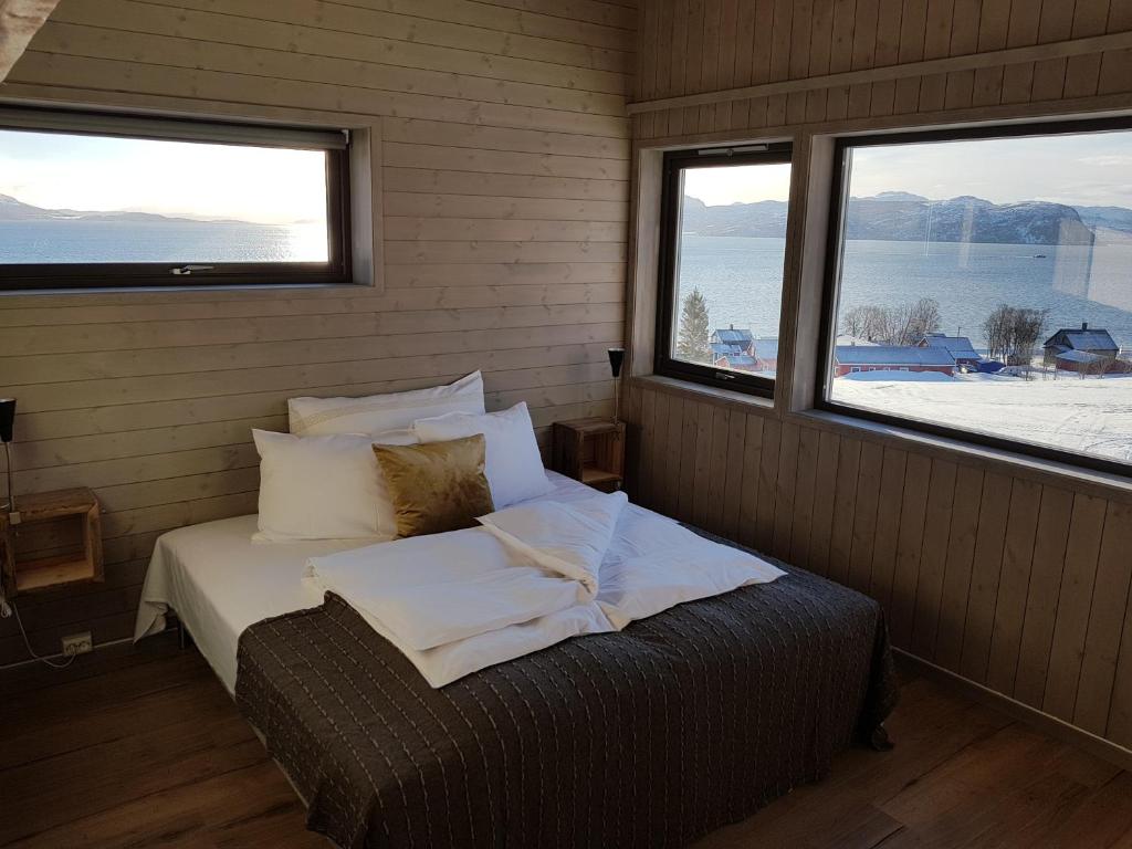 a bedroom with a bed in a room with two windows at Yggdrasil Farmhotel Retreat, Spa & Yoga in Straumsbukta