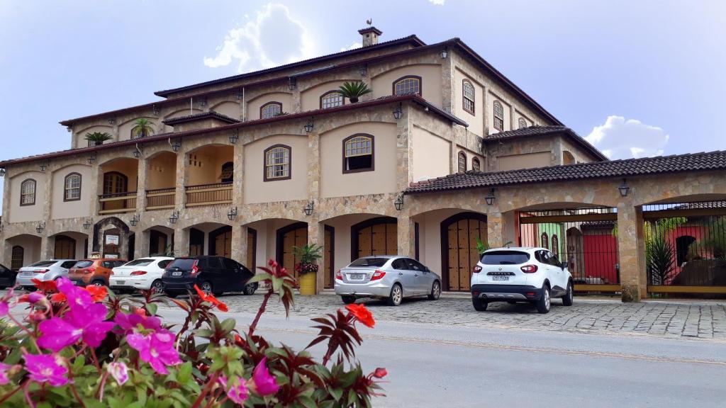 um grande edifício com carros estacionados em frente em Arraial da Lage Hospedaria em Resende Costa