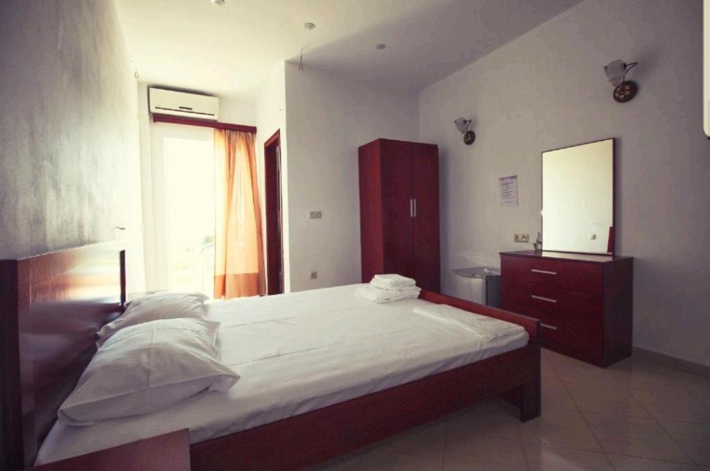 a bedroom with a bed and a dresser and a mirror at Hotel Afrodite in Dhërmi