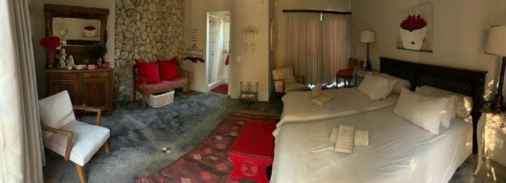 a bedroom with a large white bed and a chair at Tarentaal Guest Farm in Outjo