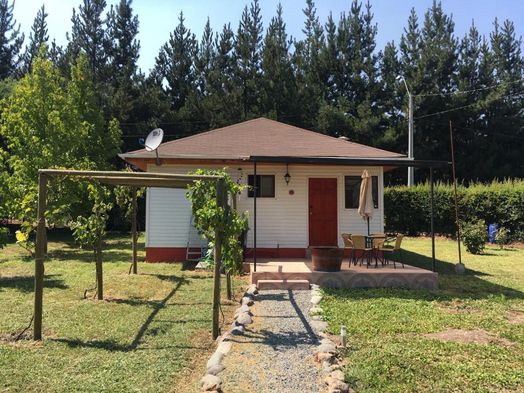 uma pequena casa branca com um alpendre e um pátio em Los Pinos de Quilvo em Romeral