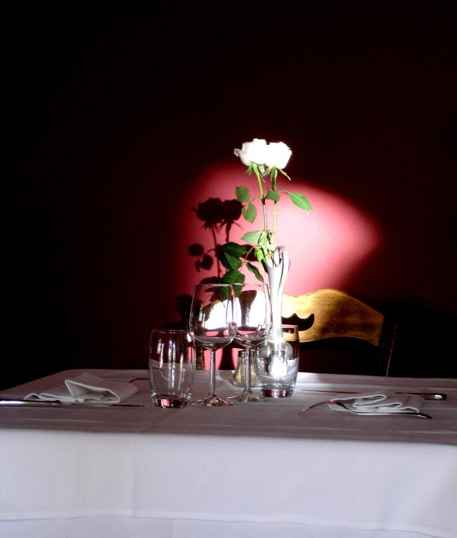 a table with a vase with flowers and glasses on it at Le Relais du Lyon d&#39;Or in Angles-sur-lʼAnglin