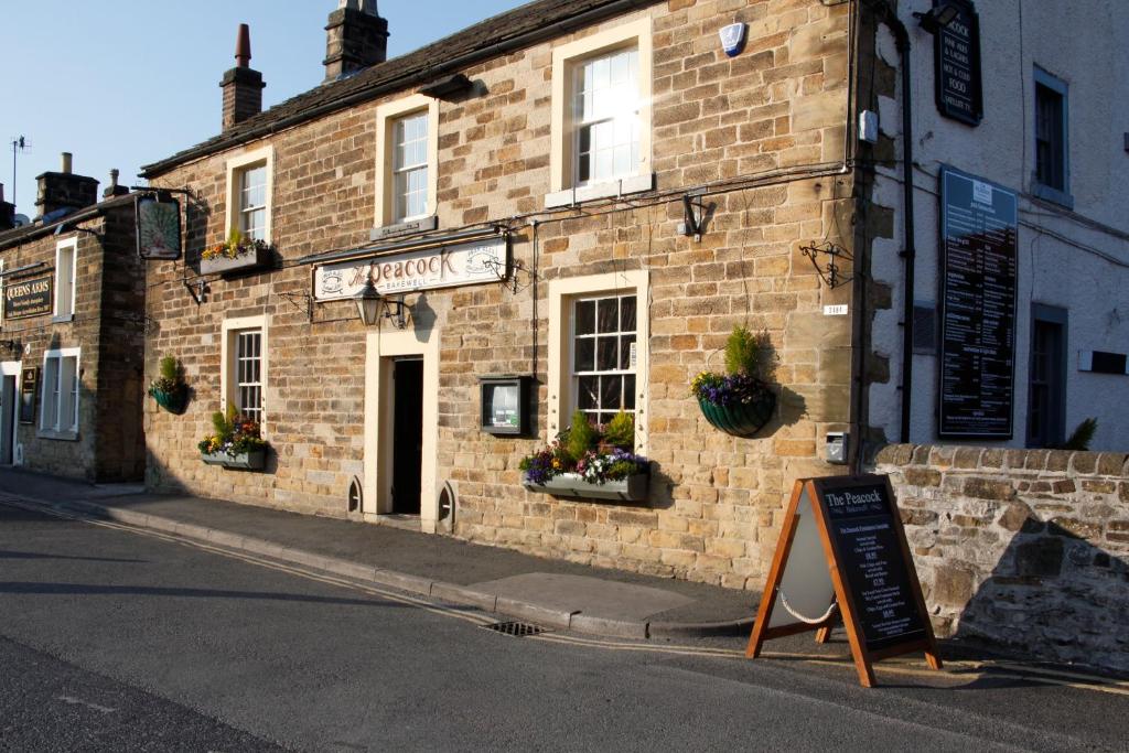 un edificio de ladrillo con un cartel delante en The Peacock, en Bakewell