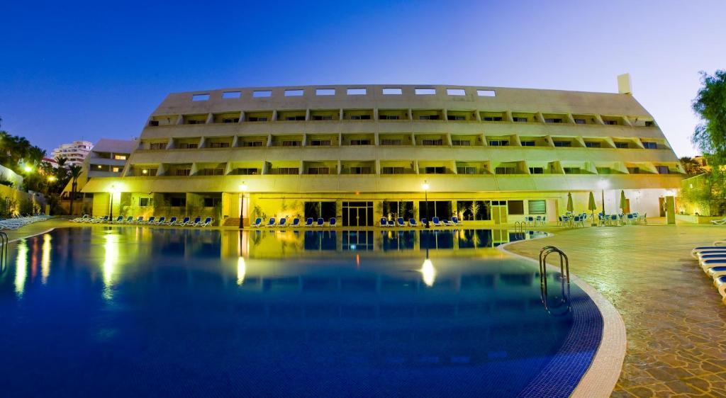 a hotel with a swimming pool in front of a building at Apartamentos Pirámides in Playa de las Americas