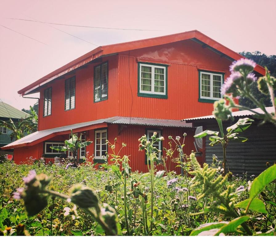 una casa roja con un jardín delante en BAEY B0GAN Homestay, en Sagada