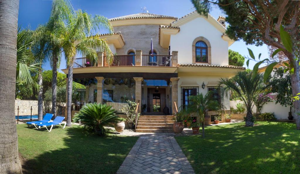 una casa con palmeras delante en Hotel Azalea Playa en Chiclana de la Frontera