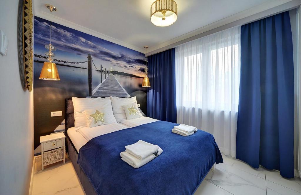 een slaapkamer met een blauw bed en handdoeken bij Sea Apartment Leśne Tarasy in Dziwnówek