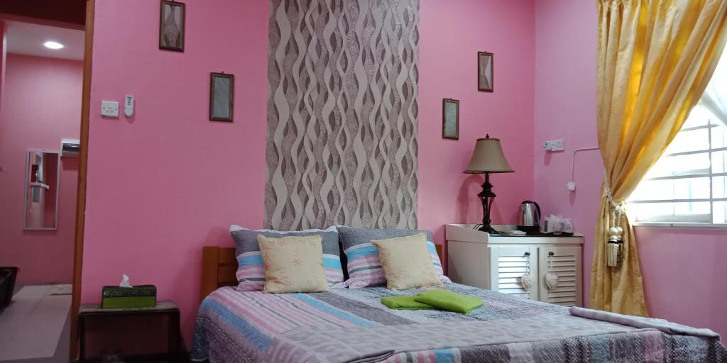 um quarto com paredes cor-de-rosa e uma cama grande em Jazepuri - Jaze 3 em Kuching